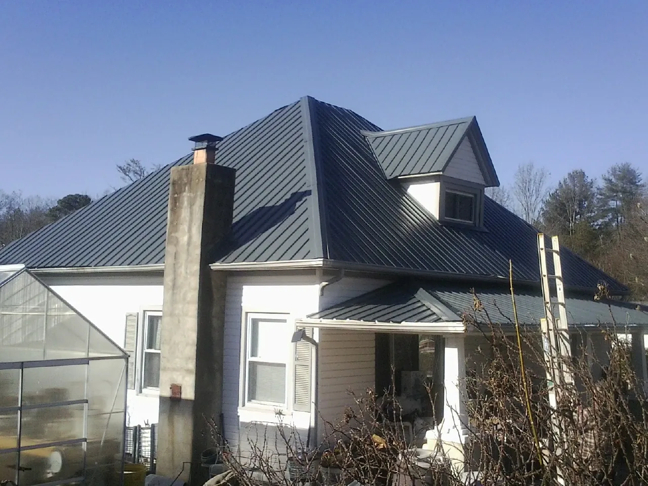 Dark blue standing seam metal roof on a white farmhouse with dormer — Slate & Tile Roof Repair by Roofing Brothers in Smithton