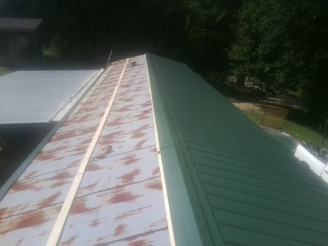 Old rusted panels beside newly installed green metal roofing — Wind Damage Roof Repair by Roofing Brothers in Smithton