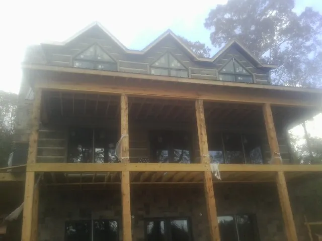 Dormers and porch framing on a large log home under construction — Roof Coating work by our crew in Smithton