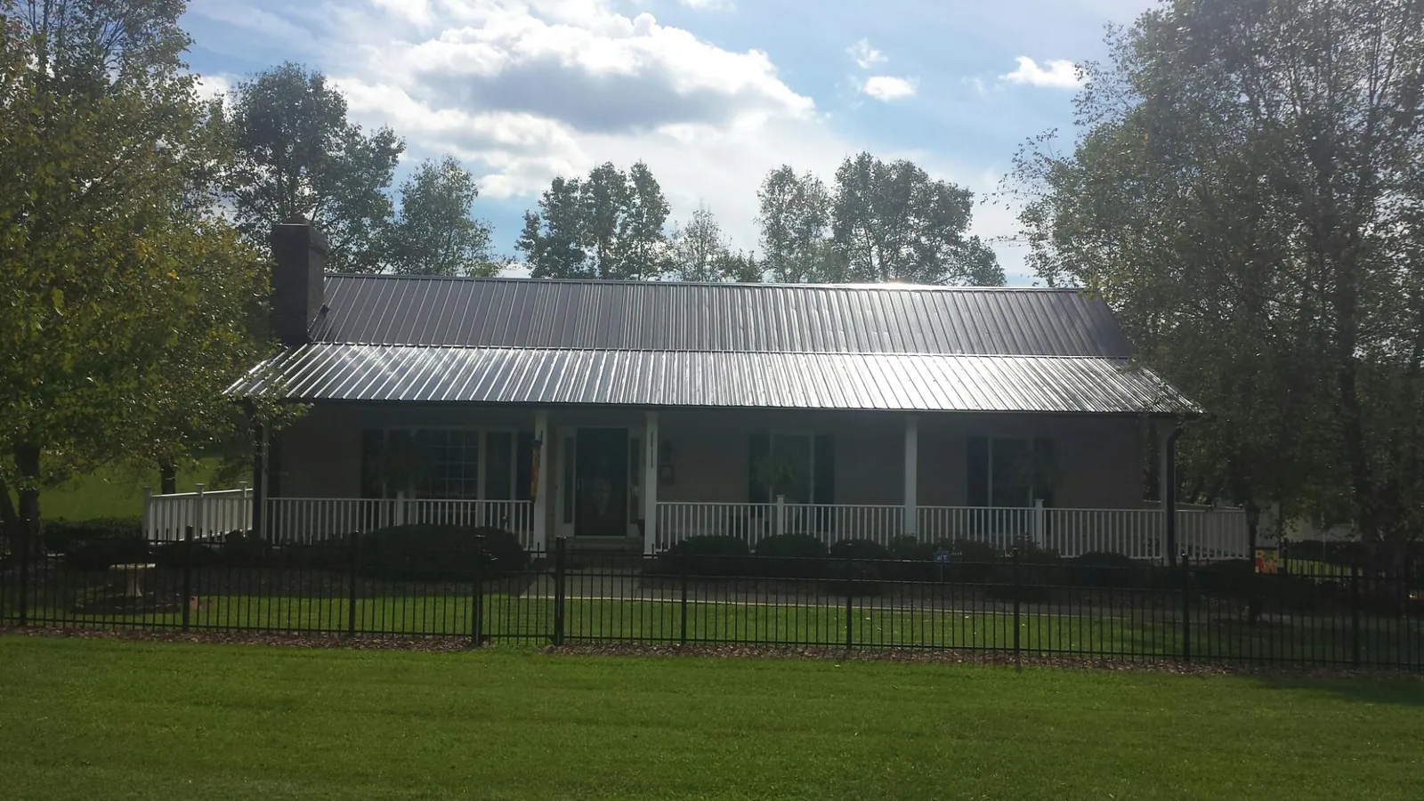 Gray metal roof on a brick ranch with a full width front porch — Gutter Guard Installation work by our crew in Smithton