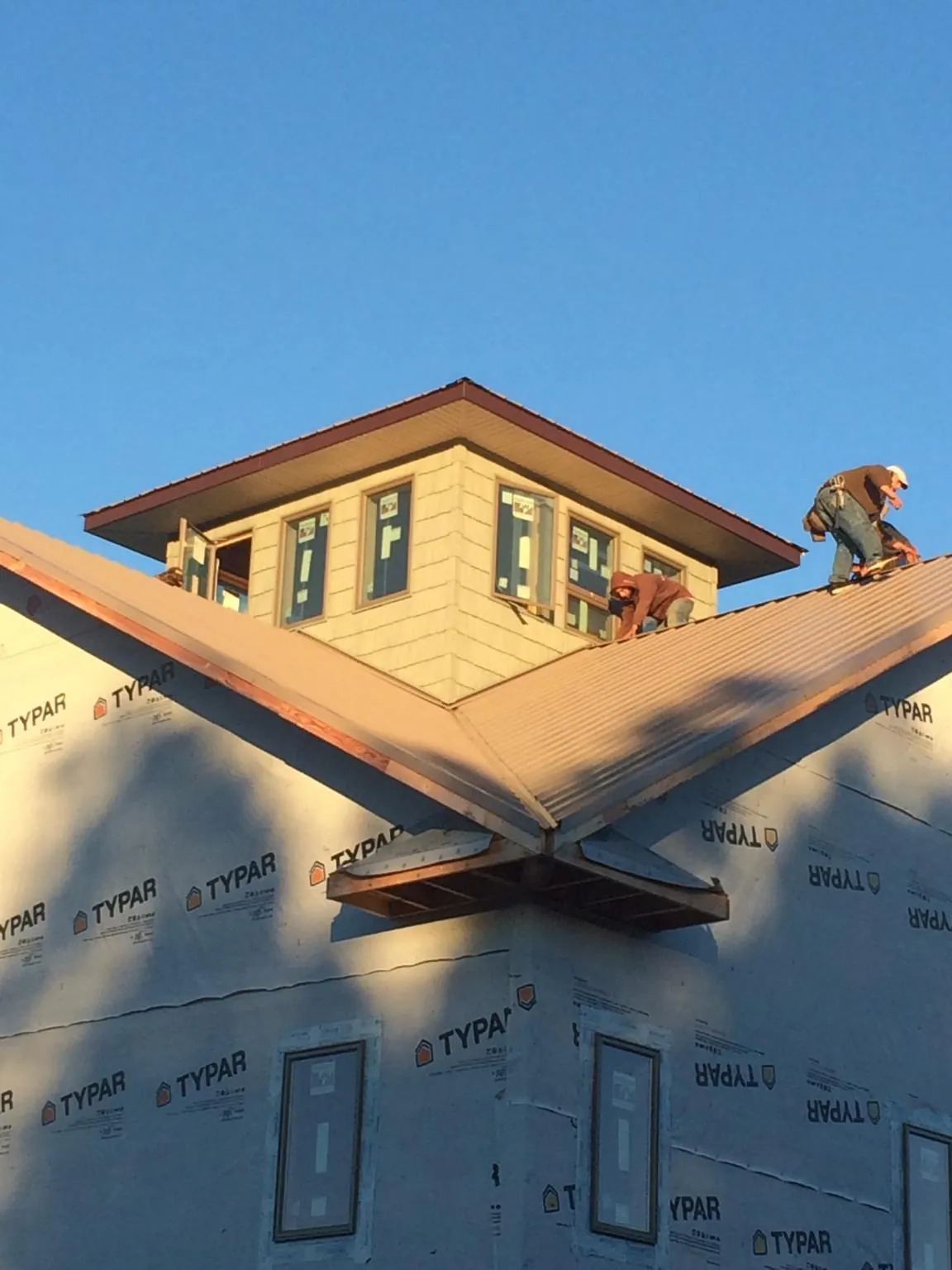 Roofers working around a rooftop cupola on a new metal roof at sunset — Roof Waterproofing in Smithton by Roofing Brothers